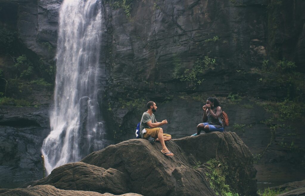 Couple sitting near a majestic Kerala waterfall during their nature escape – Kerala Luxury Trip