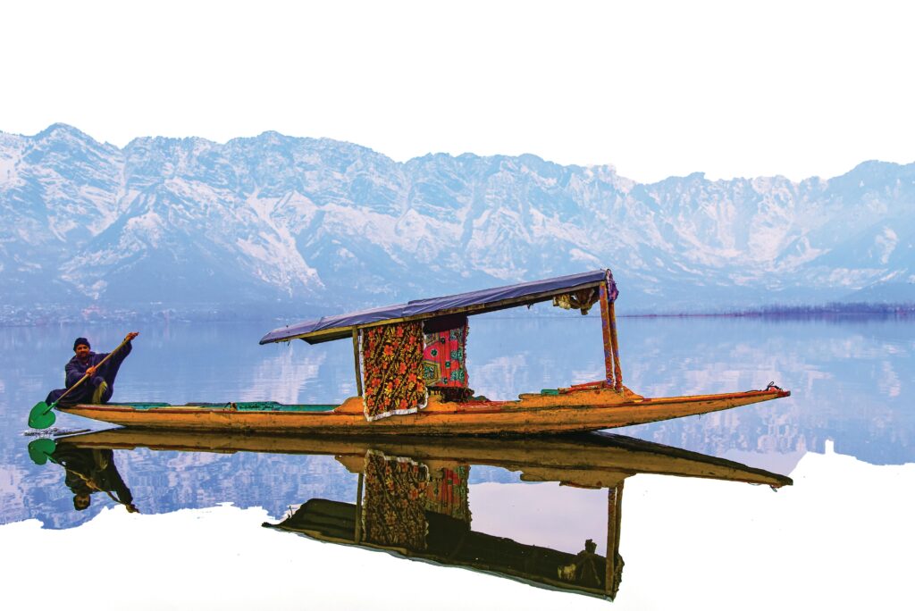 Traditional Shikara boat on Dal Lake with snow-covered Himalayas in the background, Kashmir, India