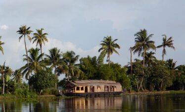 Kerala houseboat sailing along backwaters lined with palm trees – Kerala Luxury Trip
